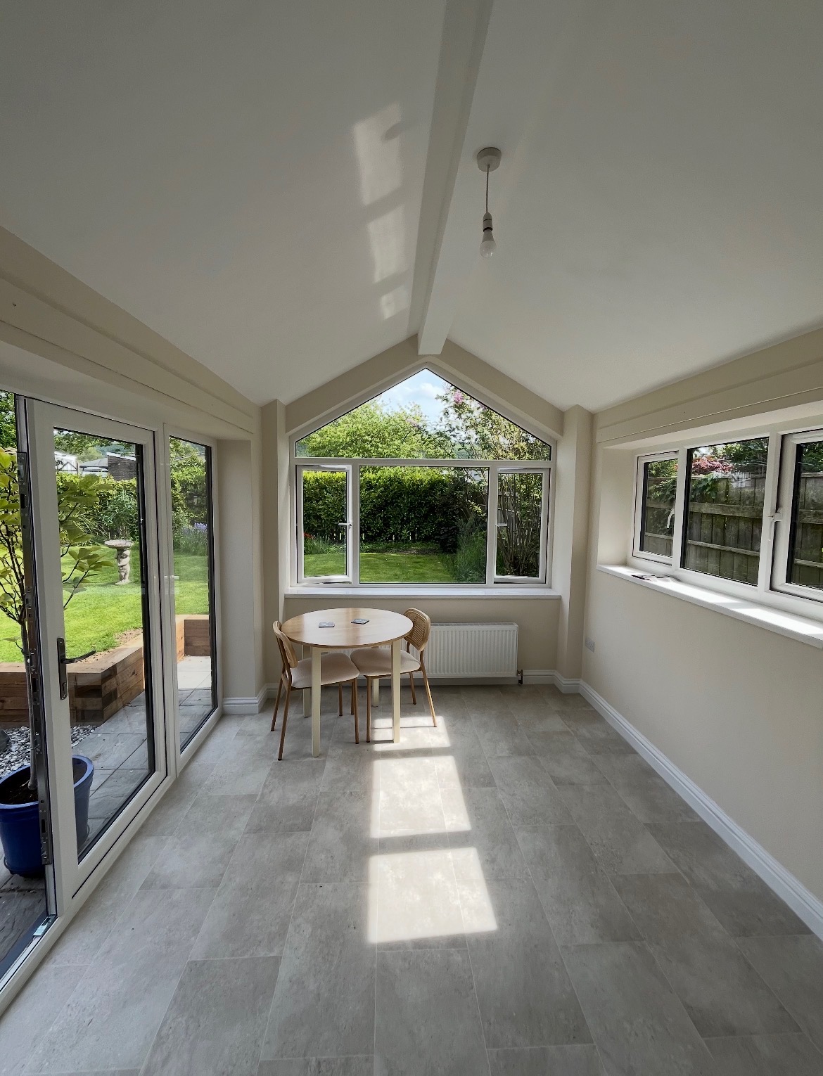 Bright renovated garden room interior with tiled floor and garden views